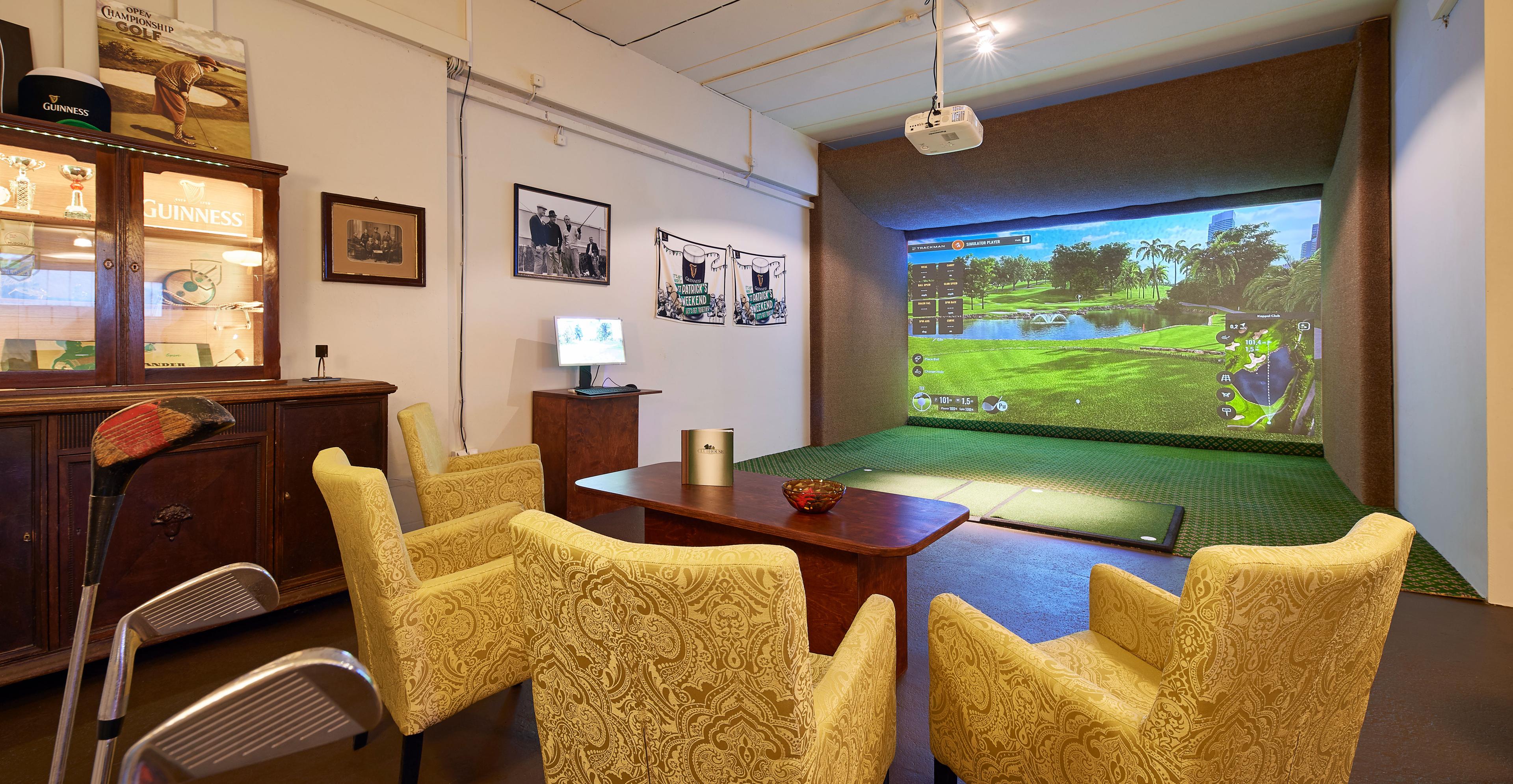 Simulator-Abschlag mit Guinness-Vitrine, gelben Paisley-Sesseln und Trackman-Leinwand