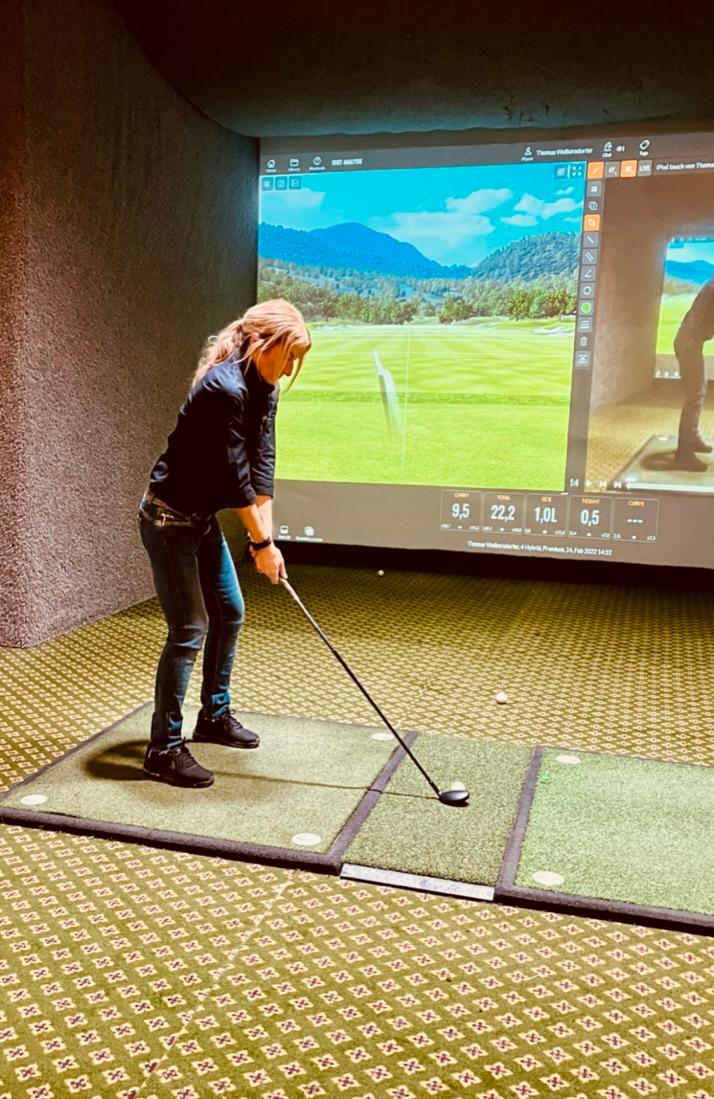 Spielerin am Abschlag vor der Trackman-Leinwand mit Videoanalyse