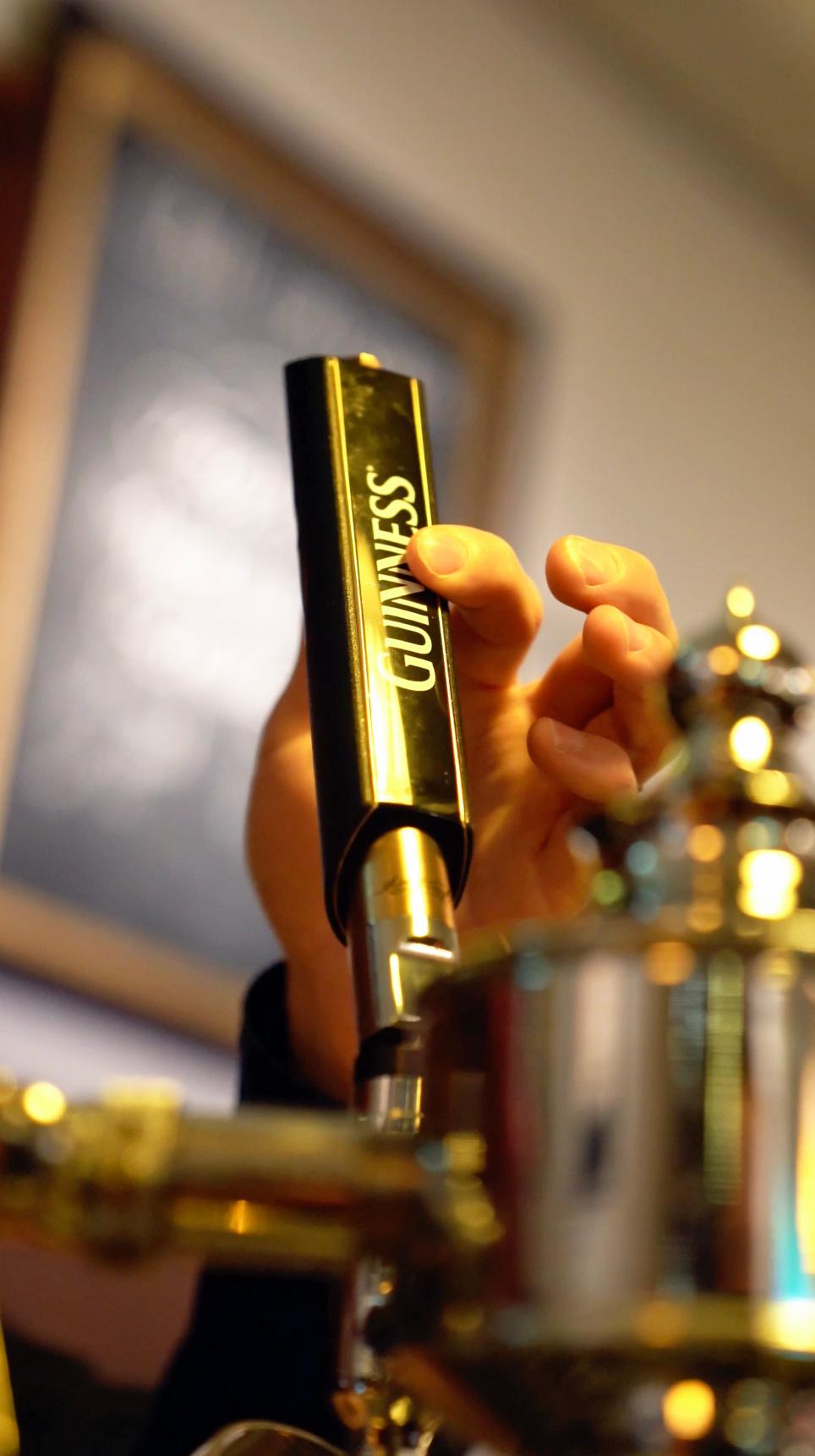 Hand am Guinness-Zapfhahn der Messing-Zapfanlage