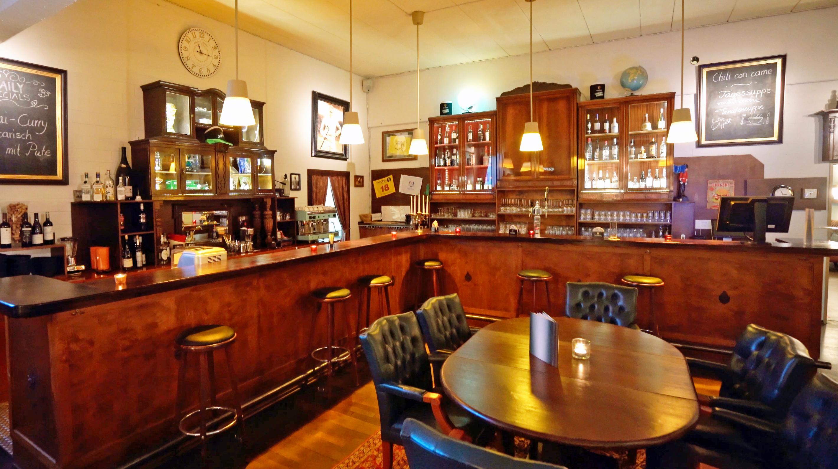 Bar-Theke mit Vitrinen, Kreidetafeln und grünen Lederstühlen